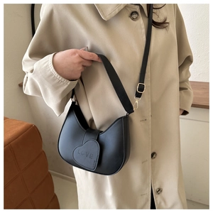 Détail d'un sac demi-lune en cuir noir mat avec un motif de cœur d'amour embossé