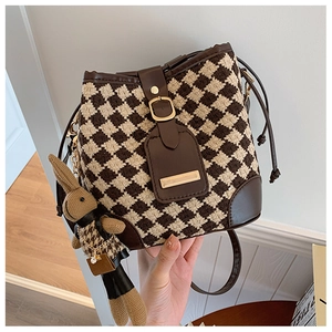 Detailed close-up of brown quilted bucket bag with tweed fabric and plush rabbit charm