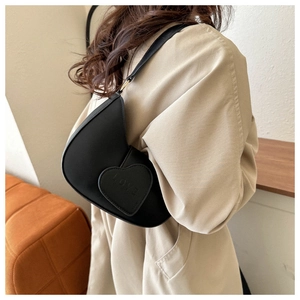 Détail du sac à bandoulière noir en forme de croissant avec une poche cœur et empreinte LOVE