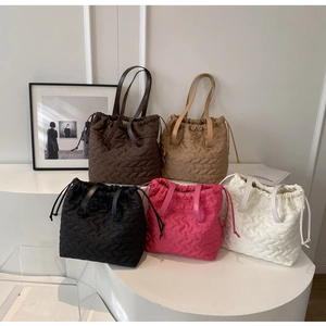 Five assorted colors of quilted drawstring nylon tote bags displayed on a tiered pedestal