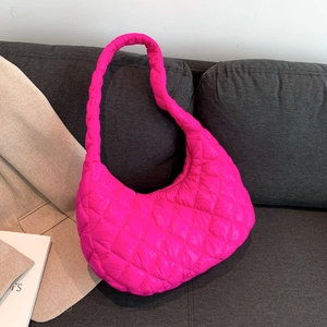 Bright pink quilted hobo tote bag in a padded diamond pattern on a soft grey sofa