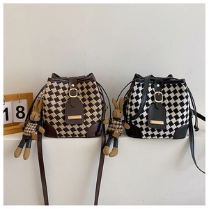 Détail de sacs seaux tricotés avec motif à damier, garniture en cuir et breloques lapin