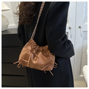 Détails du sac à bandoulière en cuir marron avec cordons, nœuds et chaîne argentée