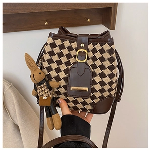 Detail of retro bucket bag featuring brown leather trim and checkerboard woven texture