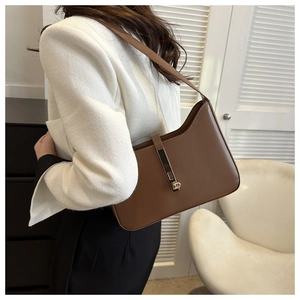 Detail of warm brown PU leather shoulder bag with gold clasp shown on model