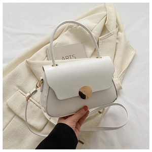 Detail of white leather shoulder bag with gold metal buckle on beige blazer texture