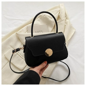 Detail of minimalist black faux leather handbag with gold round buckle and top handle