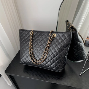Large black quilted tote bag with golden chain strap for women in a lifestyle setting