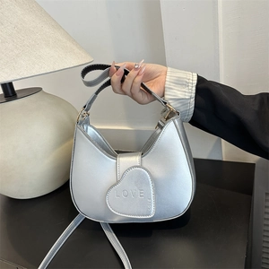 Sac sous le bras argenté en forme de croissant avec pendentif cœur et texture métallique