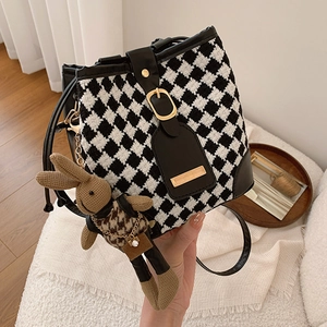 Houndstooth tweed bucket bag with leather trim and rabbit charm in home setting