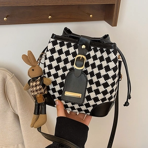 Fashionable black and white houndstooth bucket bag with bunny charm and gold buckle
