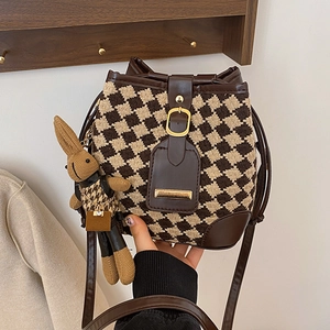 Vintage houndstooth bucket bag with leather trim and rabbit charm in hand-held pose