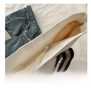 Dettaglio della cerniera in metallo e della fodera interna di borsa in tela beige