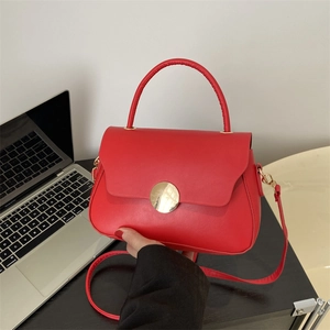Chic red faux leather crossbody bag with a large golden buckle on a laptop background