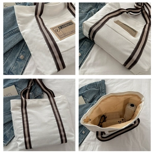 Dettaglio della borsa tote in tela crema con manici a righe ed etichetta in pelle retrò