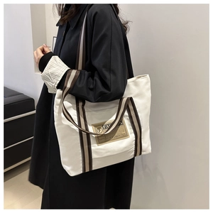 Dettaglio della borsa tote in tela bianca con manici a righe e toppa fashion vintage