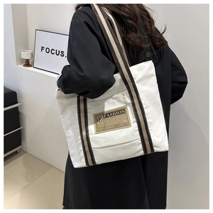 Vista dettagliata della borsa tote in tela bianca con spalline a righe sulla spalla