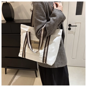 Dettaglio della borsa tote in tela bianca con manici a righe e toppa retrò fashion