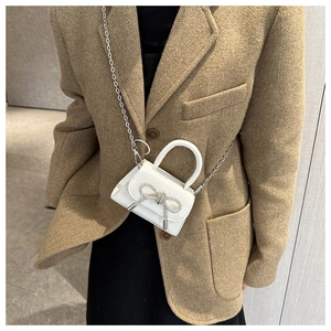 On-body shot of white mini handbag with sparkling rhinestone bow and silver chain strap