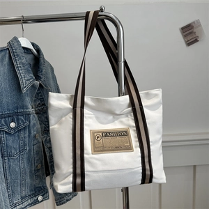 Borsa tote minimalista in tela bianca con manici a righe e etichetta alla moda