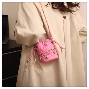 Detail der rosa gesteppten Beuteltasche mit goldenen Herzanhängern und Kettengurt