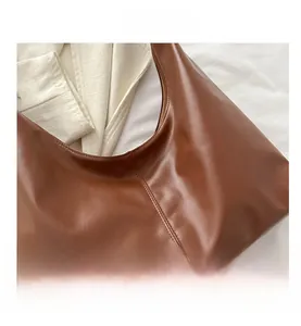 Close-up of brown leather shoulder bag featuring vertical stitching and soft texture