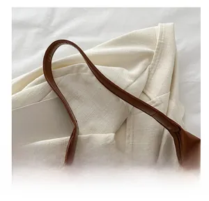 Detail showing the comfortable wide leather shoulder strap on a brown tote bag