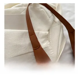 Macro shot showing high-quality stitching on canvas tote bag with brown leather straps