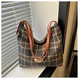 Gros plan du sac cabas rétro à carreaux avec lanières en cuir brun et logo de mode