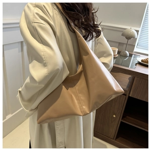 Detailed side view of beige matte leather tote bag worn by a model in a beige trench coat