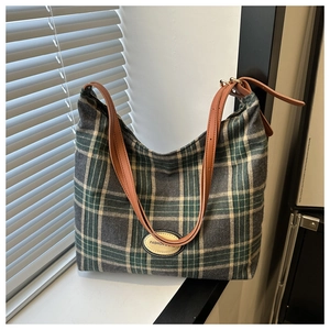 Détail du sac cabas en tartan à carreaux verts et gris avec des anses en cuir marron