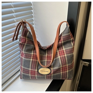 Détail du sac cabas en toile à carreaux rouge et gris avec anses en cuir marron