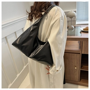 Detailed view of large black faux leather underarm bag with central vertical stitching