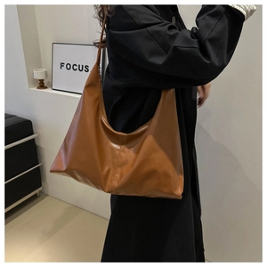 Brown soft PU leather half-moon shoulder bag styled on a model with a black jacket