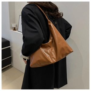 Detailed view of caramel brown soft leather tote bag worn with a black wool coat