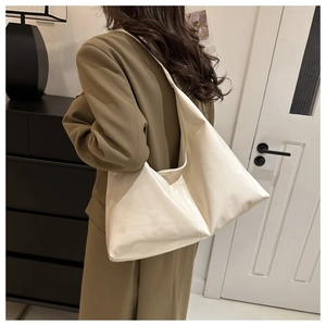Close-up of a soft cream leather tote bag paired with a professional brown blazer