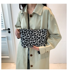 Close-up of stylish black and white leopard print canvas clutch held by a model