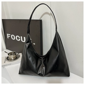 Detail of black faux leather shoulder bag featuring smooth glossy texture and wide strap