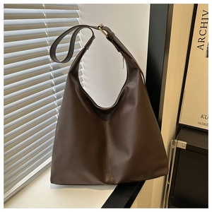Detail of dark brown leather tote bag with adjustable strap and golden metal buckle