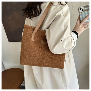 Detail of brown plush tote bag featuring faux leather straps and FASHION logo embroidery