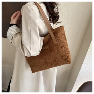 Detail of plush brown tote bag featuring faux leather shoulder straps and fashion logo patch