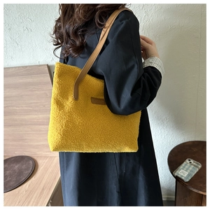 Detail of yellow fuzzy fleece tote bag with brown leather strap worn by a model
