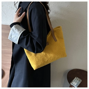 Detail of plush yellow fleece tote bag with brown leather straps and fashion label