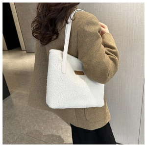 Close-up of white plush teddy tote bag with brown fashion leather tag and strap