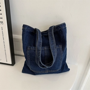 Large dark blue denim tote bag with contrast stitching and front pocket on white background