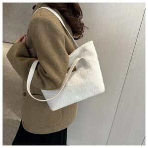 Detail of plush faux shearling shoulder bag with leather strap and small brown side tag