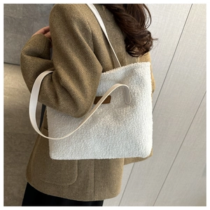 Close-up of white plush tote bag with brown leather FASHION tag and faux leather straps