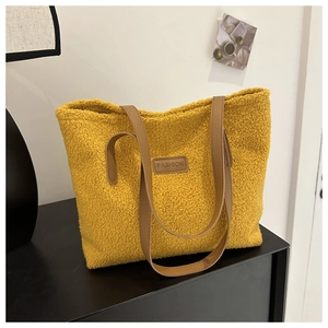 Close-up of fluffy yellow sherpa tote bag featuring a brown leather fashion tag
