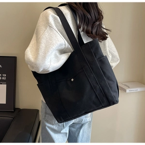Detail of spacious black canvas tote bag with side pocket and snap button closure