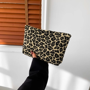 Fashionable leopard print woven clutch bag with zipper closure shown held by hand